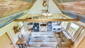 Un interior rústico con cocina, zona de estar y una viga de madera grande.