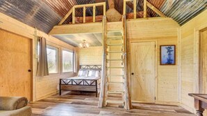 Interior de madera con cama de altillo, escalera y banco.