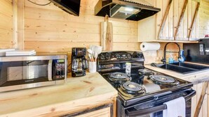 Una cocina compacta con microondas, estufa y lavamanos.
