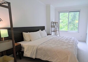 A bedroom with a bed, a nightstand, a lamp, a window, and a chair. - Quiet North Waterfront 1BR · WFH Setup · in-unit W/D · 24/7 Doorman, Gym, Sauna (San Francisco)