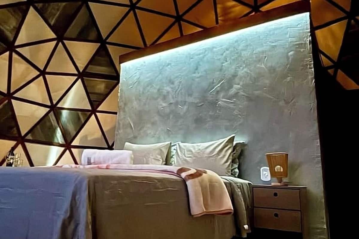 A bed with a textured headboard, a bedside table with a lamp, and a geometric wall pattern.