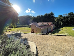 A house with a red-tiled roof, a paved driveway, and a small garden area.