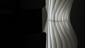 A modern, minimalist room with a sleek, white, curved light fixture and a dark-toned electronic device on a table. - STAYUP ILSAN Capsule Hotel (Goyang)