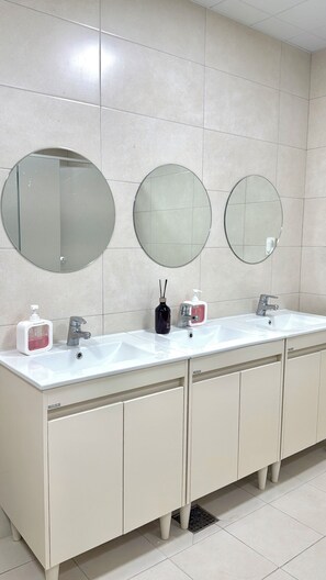 Un baño con dos lavamanos, tres espejos y un revestimiento de azulejos.