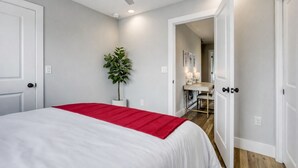 A bedroom with a bed, a ceiling fan, a potted plant, and a hallway leading to a bathroom. - 4BR Austin Home, Minutes to Downtown, Parking, Sleeps 10 (Austin)