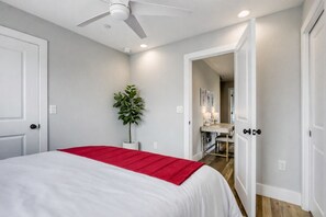 A bedroom with a bed, a ceiling fan, a potted plant, and a hallway leading to a bathroom. - 4BR Austin Home, Minutes to Downtown, Parking, Sleeps 10 (Austin)