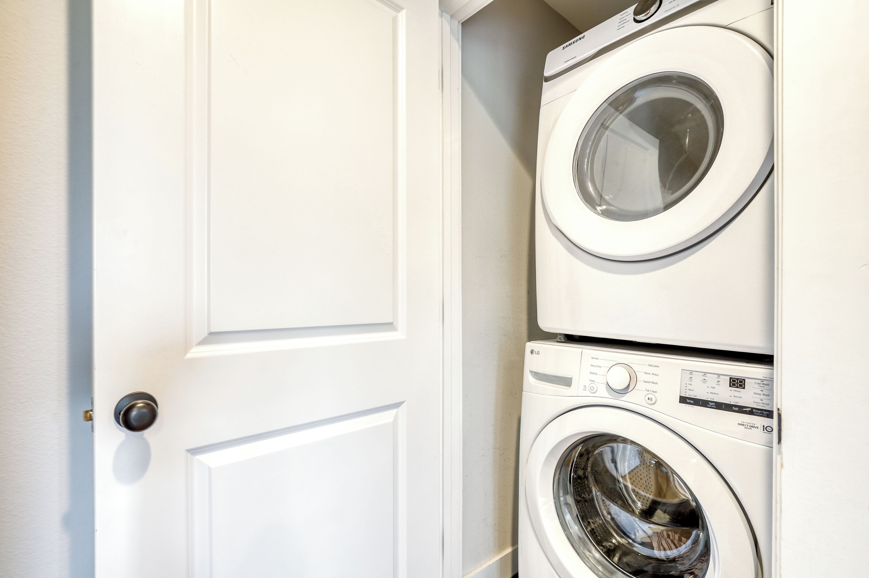 A white door with a round doorknob, adjacent to a stacked washer and dryer unit.