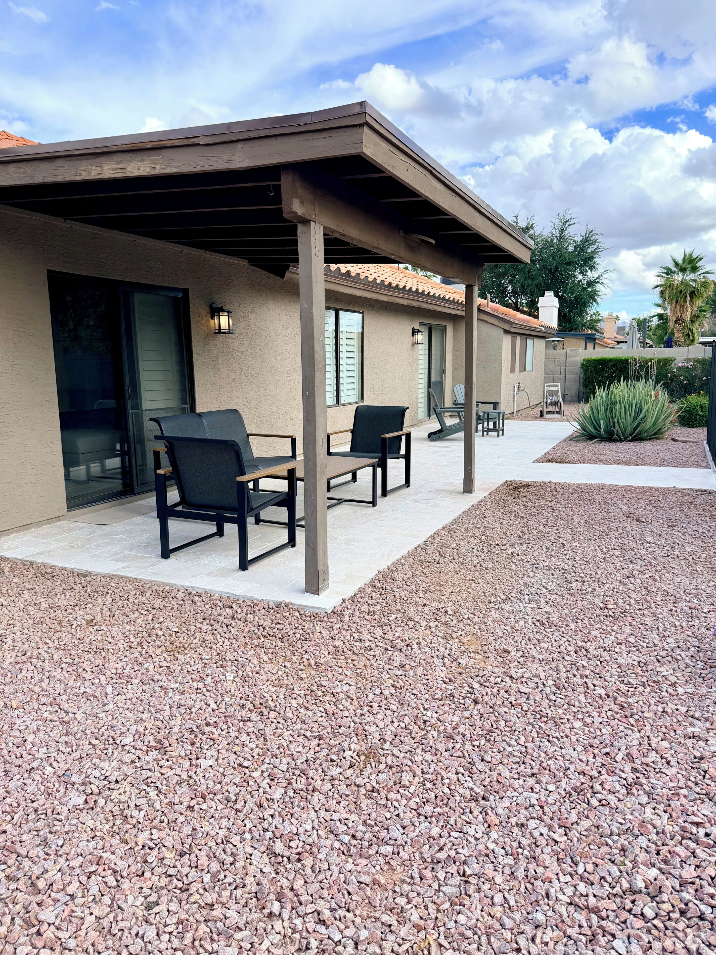 Un patio techado con mobiliario exterior y suelo de grava.