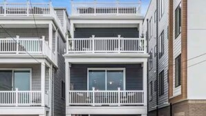 Un edifici residencial de dues plantes amb garatge, un balcó i cel blau.
