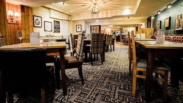 A restaurant with wooden walls, patterned carpet, and multiple dining tables with chairs. - Milsoms Hotel (Kenilworth)