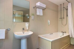 Un baño con lavamanos, espejo, toallero, ducha y bañera.
