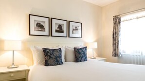 A hotel room with a large bed, two bedside tables, a nightstand, and three framed pictures on the wall. - Milsoms Hotel (Kenilworth)