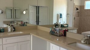 Een moderne badkamer met een grote spiegel, twee wastafels en een douche.