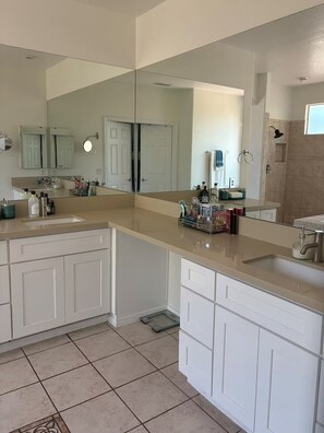 A modern bathroom with a large mirror, two sinks, and a shower area. - The Luxury Oasis (Corona)