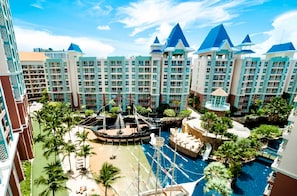 Ein Resort mit mehreren Hochhäusern, einem zentralen Poolbereich mit Wasserrutschen und Palmen.