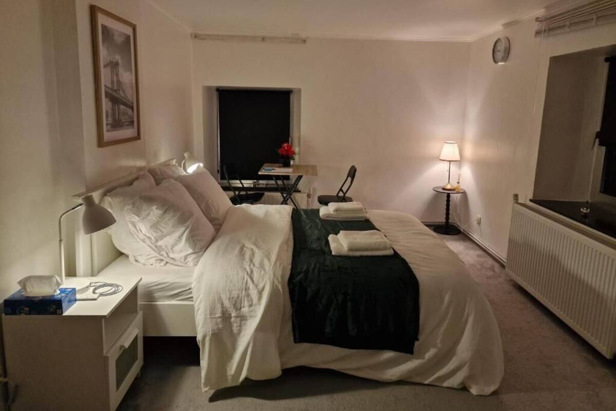 Ett hotellrum med en säng, ett sängbord, en lampa och en spegel.