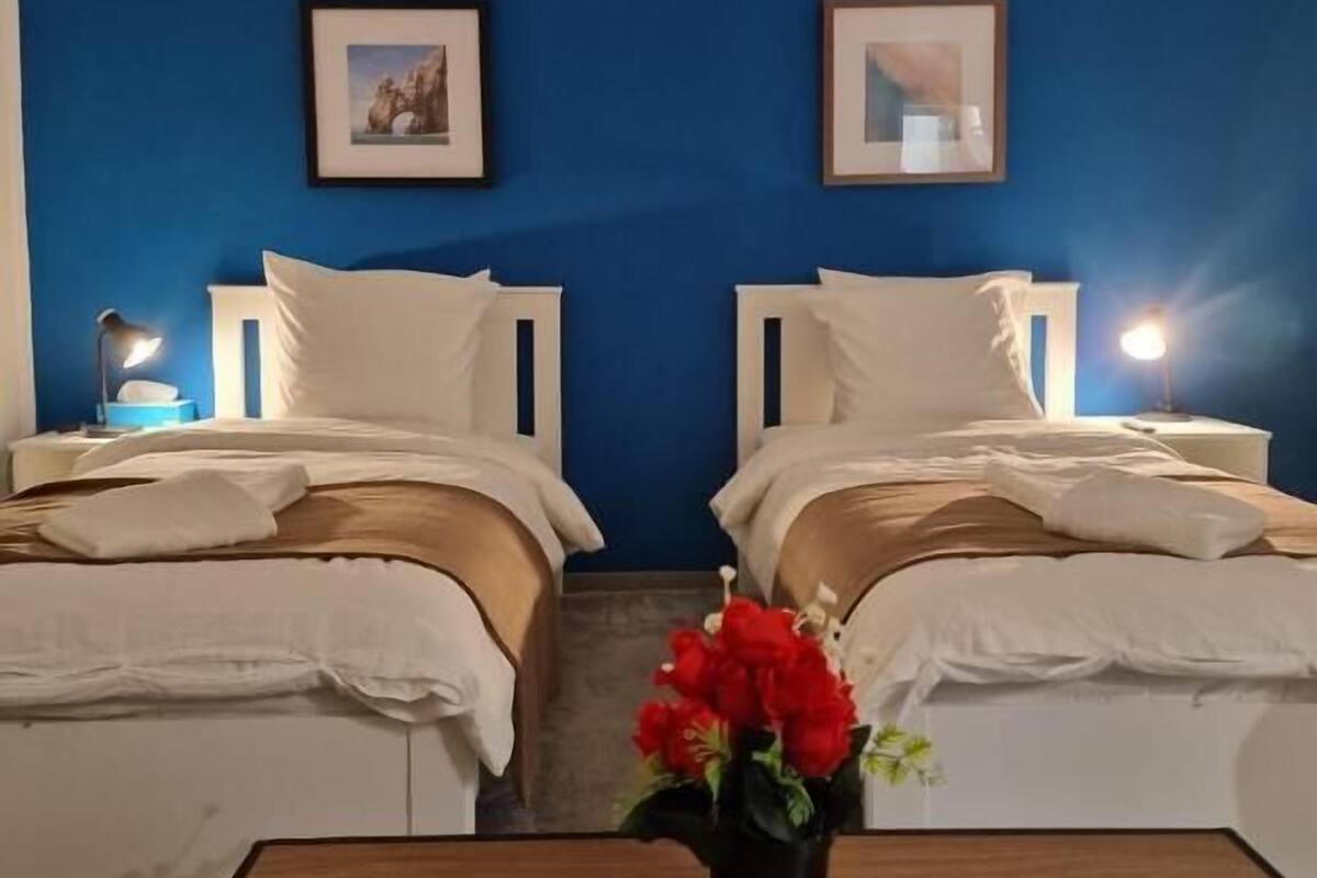 Ett hotellrum med två sängar, ett träbord och en vas med blommor.