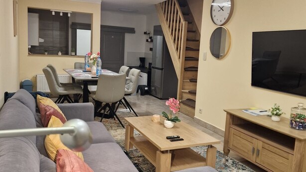 A modern living room with a grey sofa, a wooden coffee table, a TV, and a staircase. - The Famenne Escape (Marche-en-Famenne)