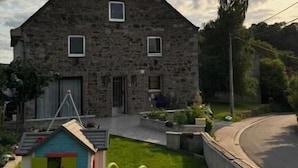 A stone house with a small play area including a slide and a playhouse. - The Famenne Escape (Marche-en-Famenne)