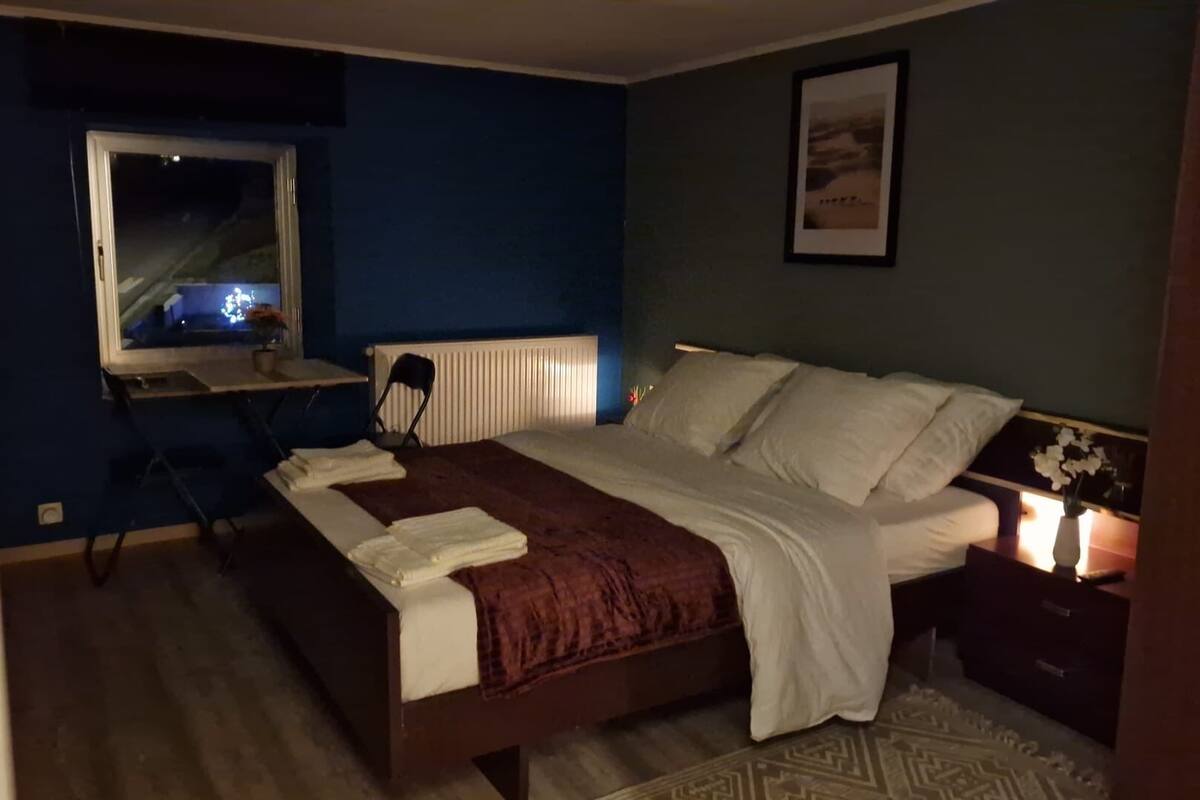 Ett sovrum med en säng, ett skrivbord, en stol och ett element.