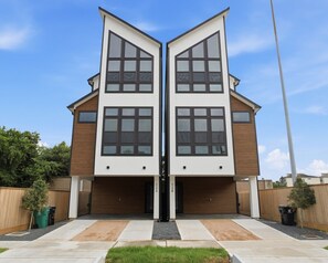 A symmetrical modern house with two garage doors, a central entrance, and a paved driveway. - Luxury 7BR/7BA Home • Houston Skyline • Downtown (Houston)