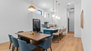 Una cucina moderna con mobili bianchi, un frigorifero nero e un'isola centrale con sgabelli da bar.