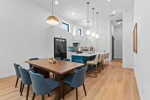 A modern kitchen with white cabinets, a black refrigerator, and a central island with bar stools. - Luxury 7BR/7BA Home • Skyline Game Room • Houston (Houston)
