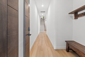 Ein Flur mit einer hölzernen Bank, einer Treppe und einer Tür mit Metallgriffen.