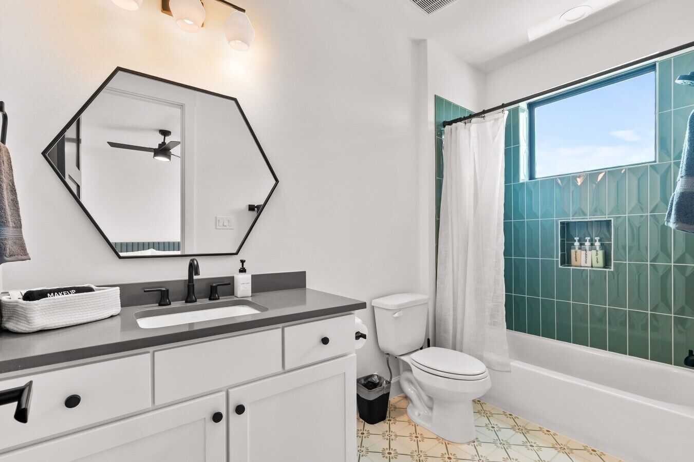 Un baño moderno con un espejo grande, un lavabo, un inodoro y una bañera.