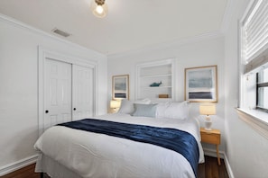 A bedroom with a bed, two bedside tables, a window, and a door.