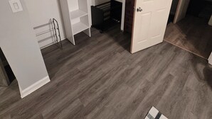 Un dressing accessible sans porte, avec un porte-chaussures et un petit meuble de rangement.