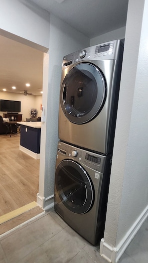 A stacked washer and dryer unit in a modern kitchen with a wooden floor and a dining area visible in the background. - Beautiful 2-bedroom house with AC in welcoming Glendale (Glendale)