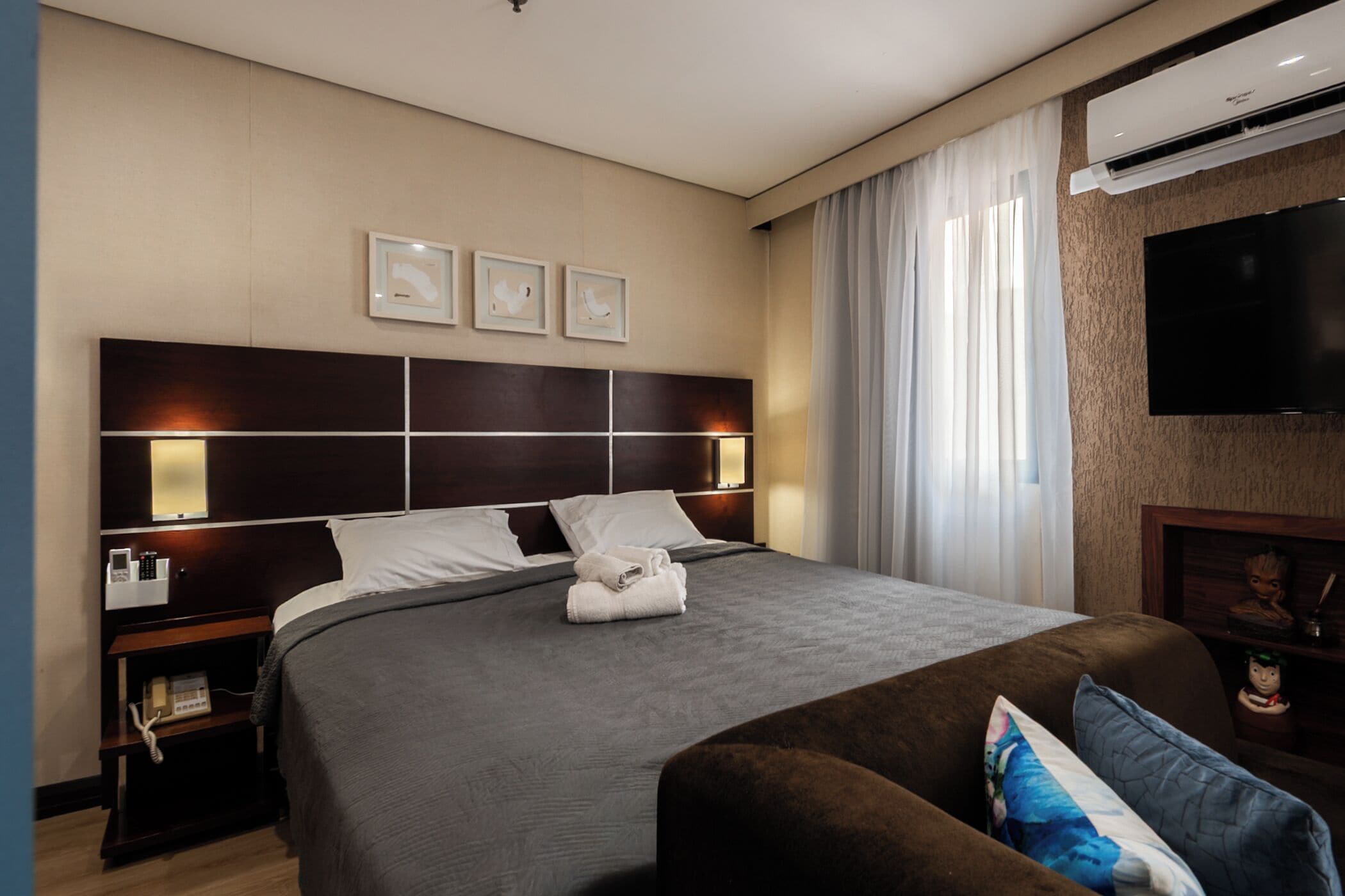 A hotel room with a large bed, bedside tables, a flat-screen TV, and a fireplace.