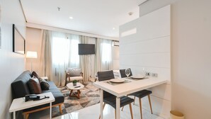 A modern living room with a sofa, coffee table, and dining area with chairs and a table. - RCT Hospedagens - Chácara Santo Antonio (São Paulo)