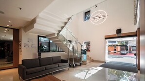 A modern lobby with a staircase, a sofa, a coffee table, and a view of the street. - RCT Hospedagens - Chácara Santo Antonio (São Paulo)