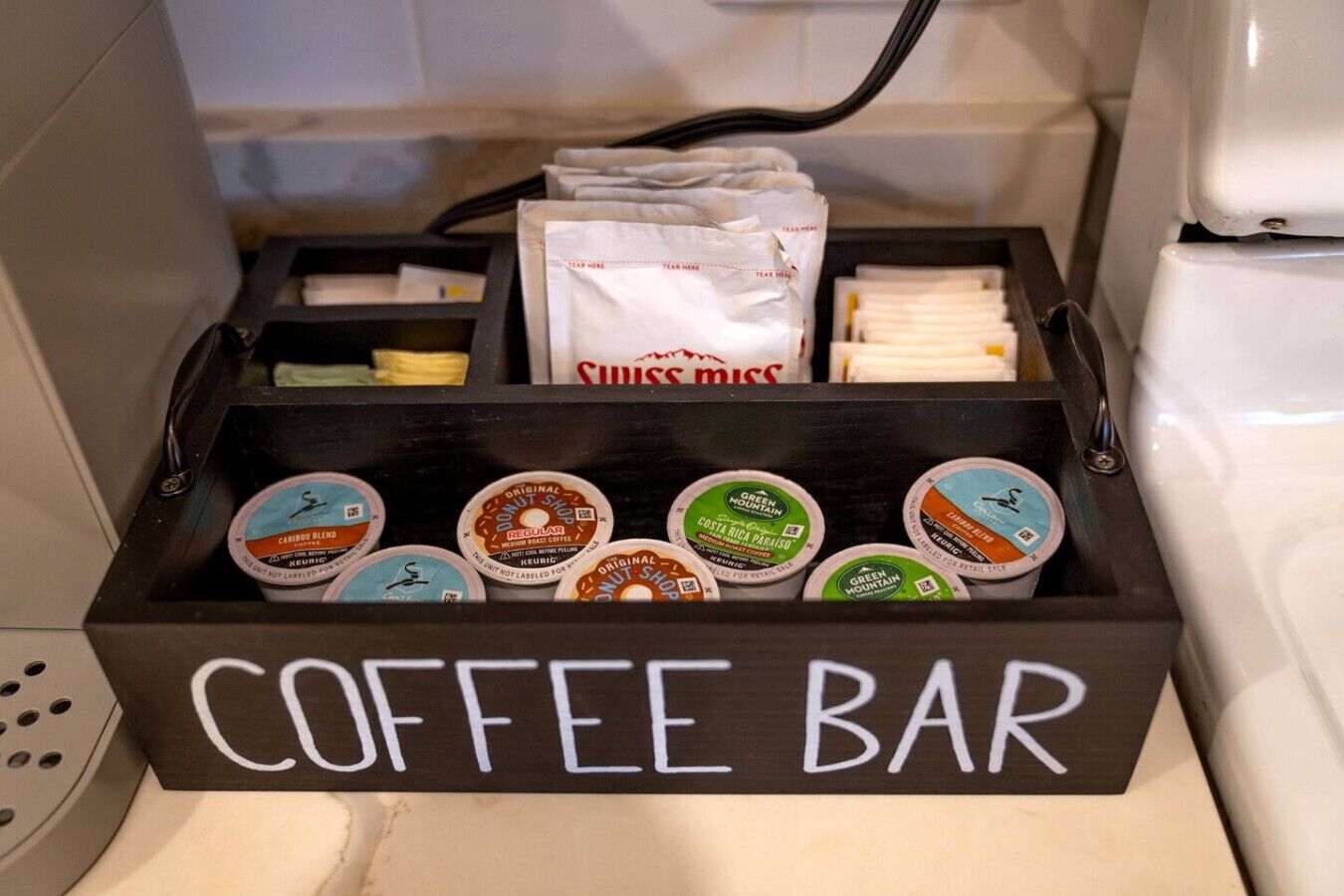 A coffee bar with labeled containers of coffee and a bag of Swiss Miss tea.