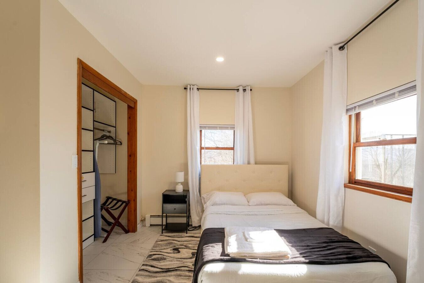Ein Schlafzimmer mit Bett, Nachttisch, Stuhl, Kleiderschrank und Fenster.
