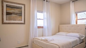 A bedroom with a bed, a painting, and a window with curtains. - 3BR Near West Point | Coffee Bar | Sleeps 6 (Highland Falls)