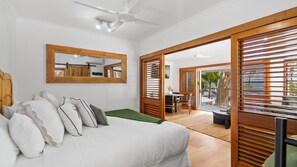 Ein Schlafzimmer mit Bett, Kissen, einem Spiegel und einer Schiebetür, die auf einen Balkon führt.