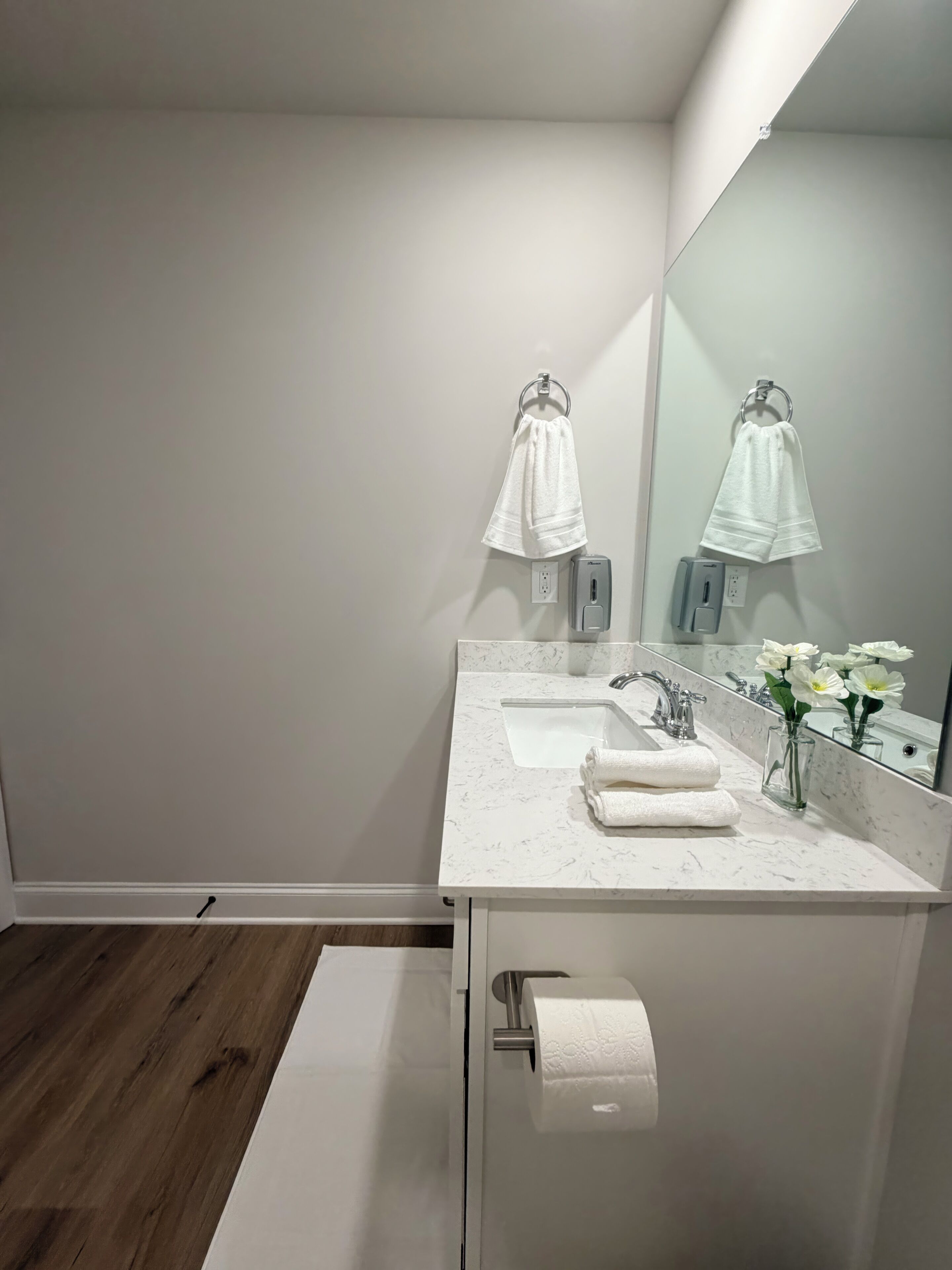 A modern bathroom with a white sink, mirror, and towel rack.