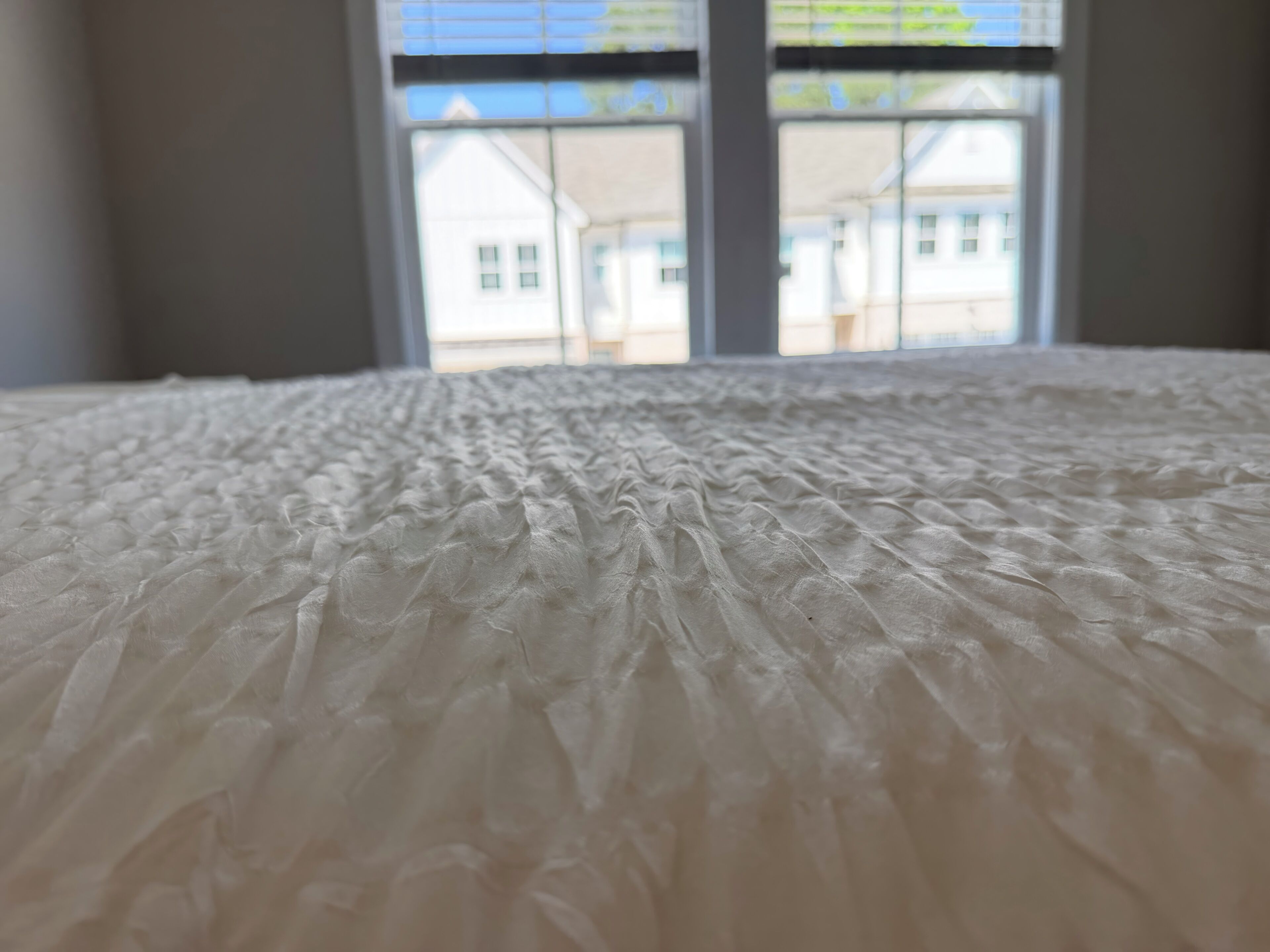 A bed with a textured white cover.