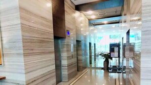 A modern hotel lobby with marble walls, a glass elevator, and a reception desk. - Luxury Studio in 38 Park Ave IT PARK (Lapu-Lapu)