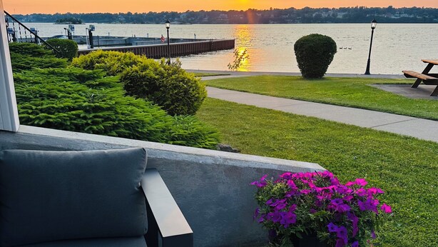 Un patio con vista a un atardecer sobre un cuerpo de agua, un poste de luz y una maceta.