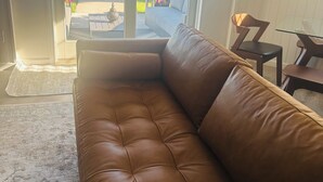 Un sofá de cuero marrón en una habitación con vista a un patio y área exterior.