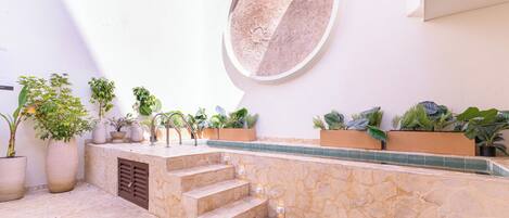 A stone staircase leading to a balcony with potted plants and a circular wall feature.