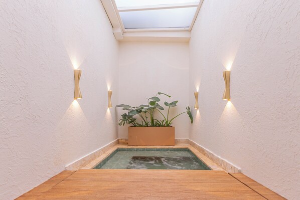 Un espacio de spa con suelo de madera, una piscina pequeña y un jardín con plantas.