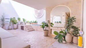 A spacious outdoor area with a stone floor, multiple potted plants, a seating area, and a stone wall with a circular design. - Casa Museo by HOUSY (Medellín)