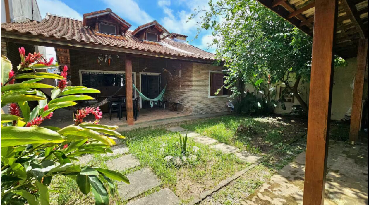 A house with a tiled roof, a hammock, and a garden with plants.