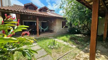 A house with a tiled roof, a hammock, and a garden with plants.