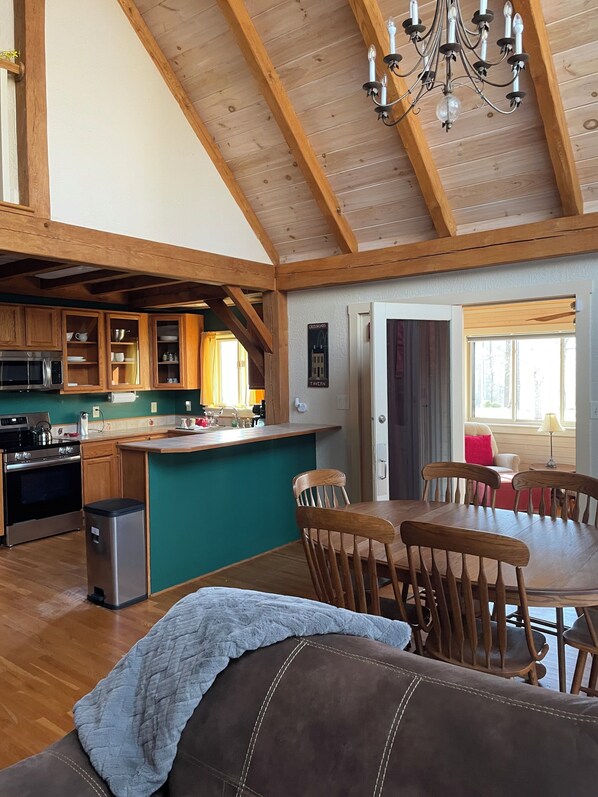 Une cuisine spacieuse avec des poutres en bois, un coin repas avec une table et des chaises, et un coin salon confortable avec un canapé.